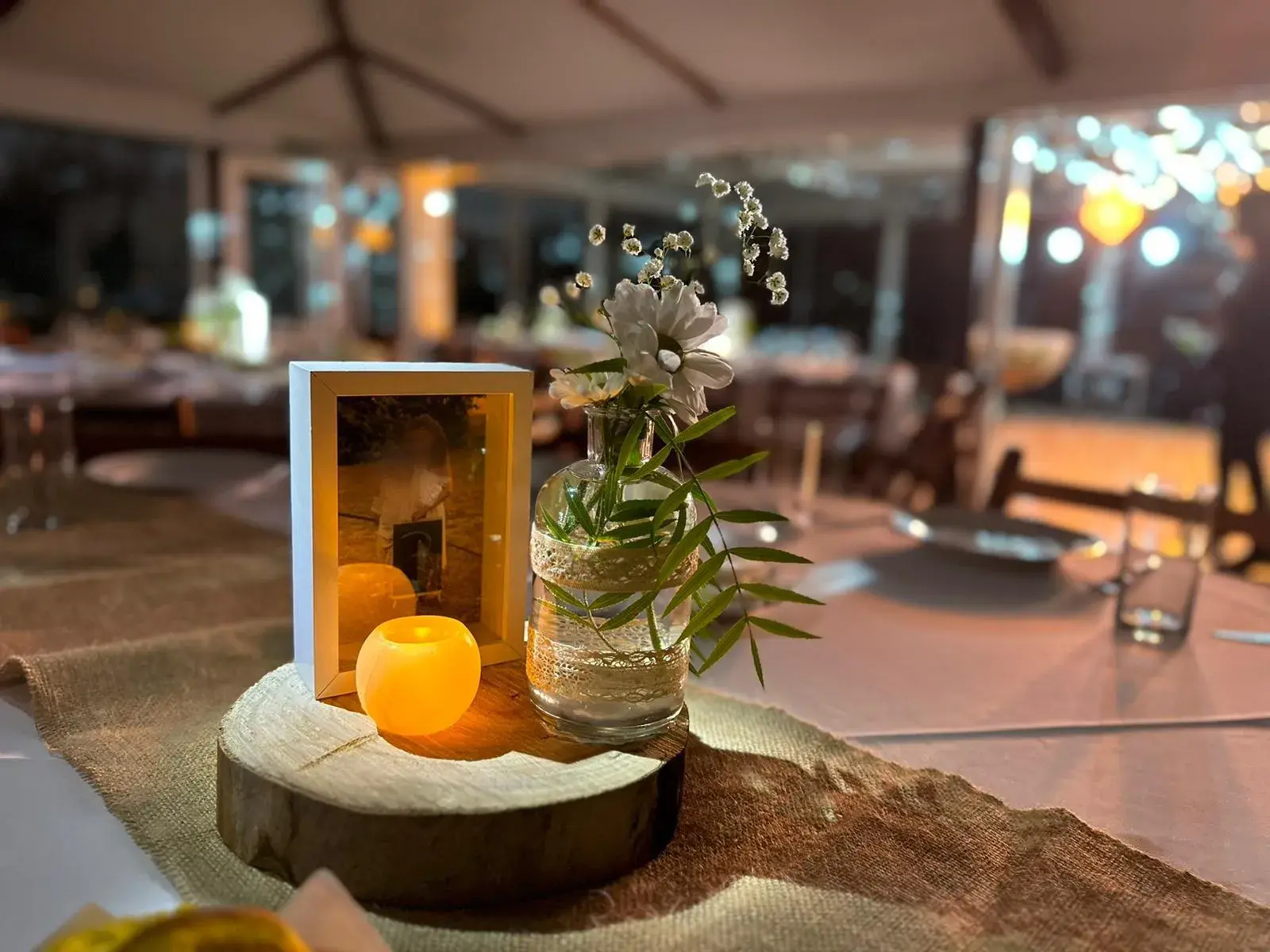 Centro de mesa con un portarretrato, una vela encendida y flores