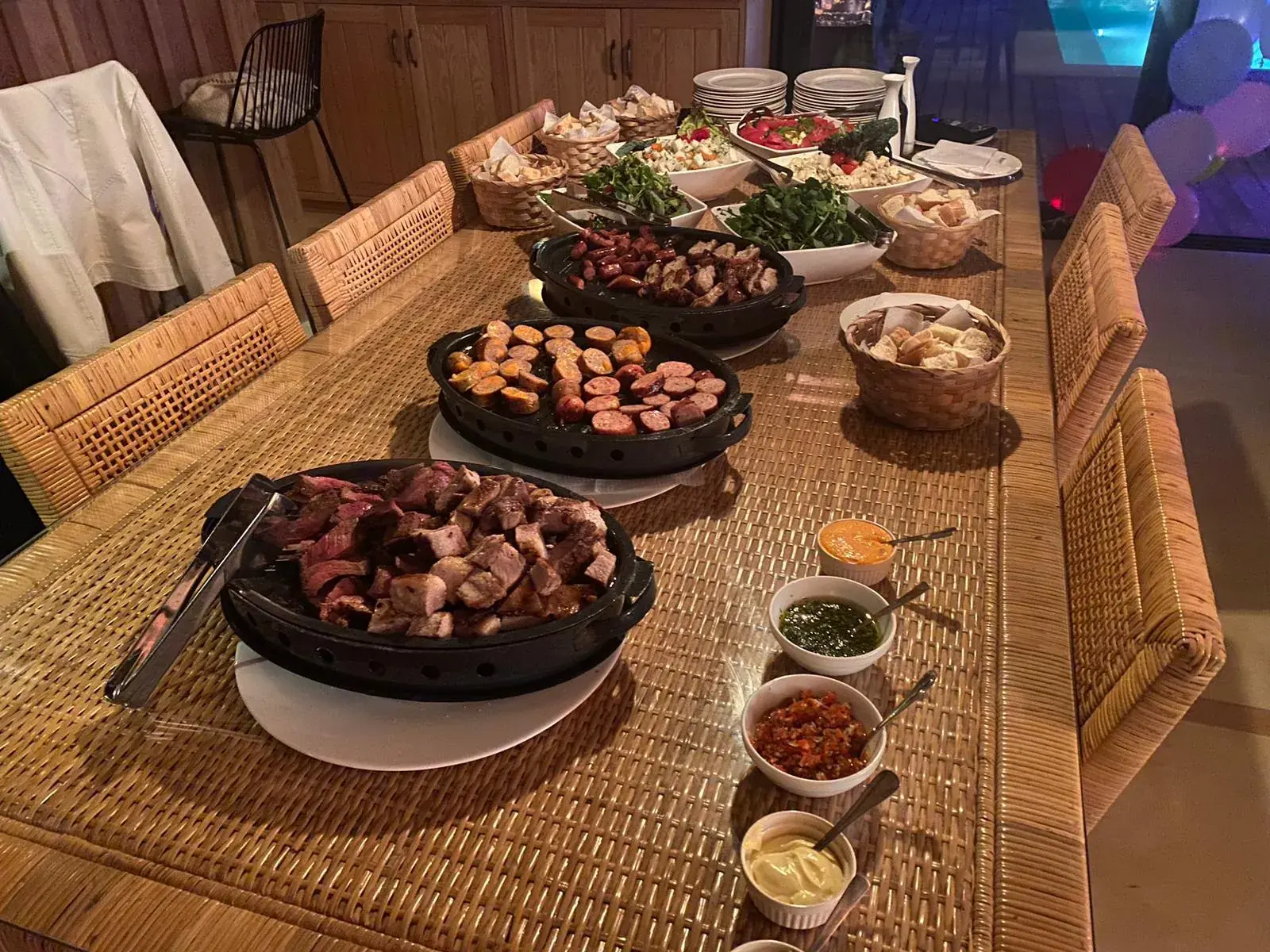 Mesa larga servida, con globos de fiesta al fondo